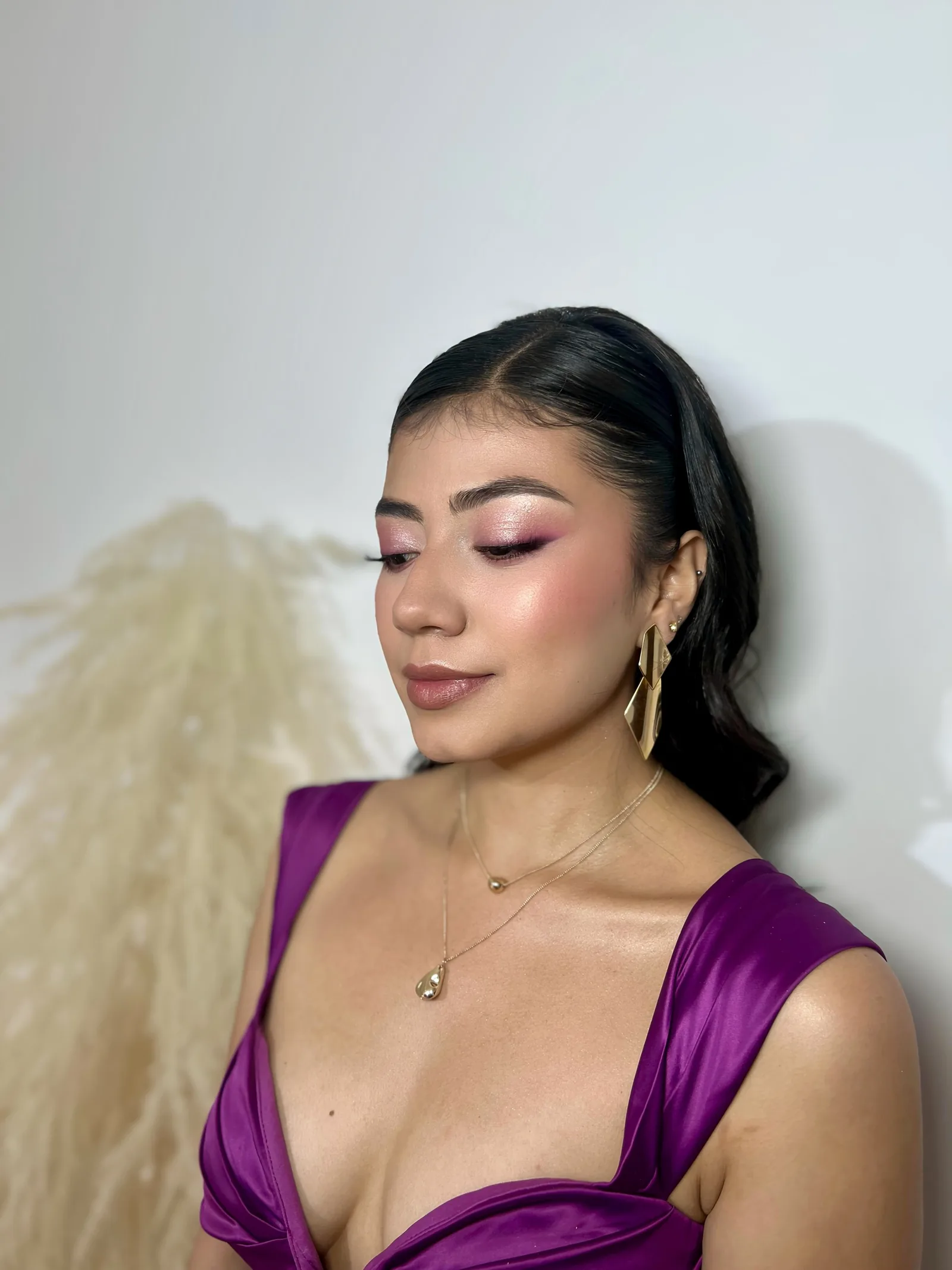 Retrato de una mujer con maquillaje rosa brillante y vestido violeta.