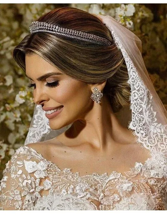 Novia con tiara, velo de encaje y maquillaje clásico, con los ojos cerrados.