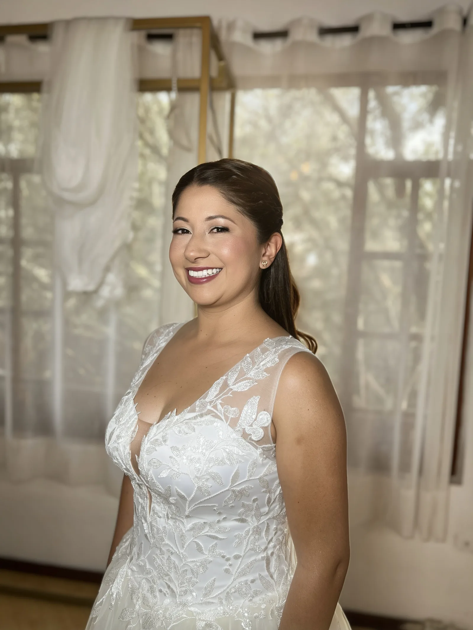 Smiling bride with elegant makeup and a white embroidered lace dress.