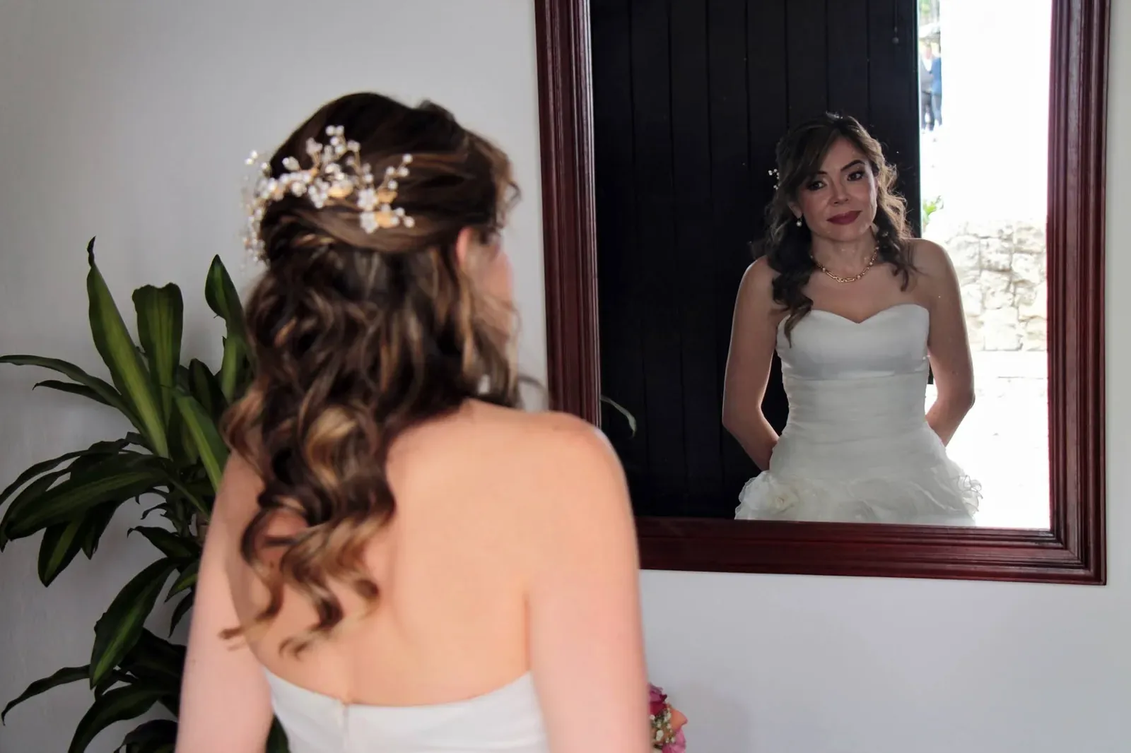 Ginita se mira al espejo con maquillaje de novia de labios intensos, semirrecogido con ondas y tocado de perlas