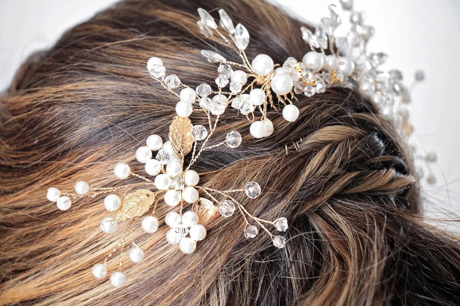 Detalle del peinado de novia de Ginita: tocado de perlas, cristales y hojas doradas sobre un trenzado suave