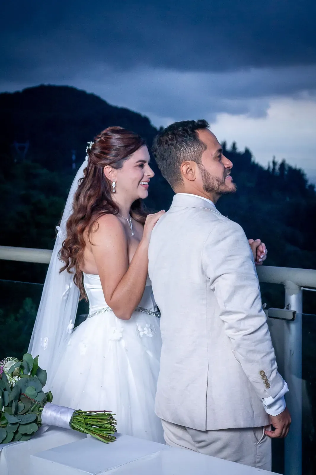 Kelly de perfil con maquillaje de novia, semirrecogido con ondas largas, velo y aretes de cristal