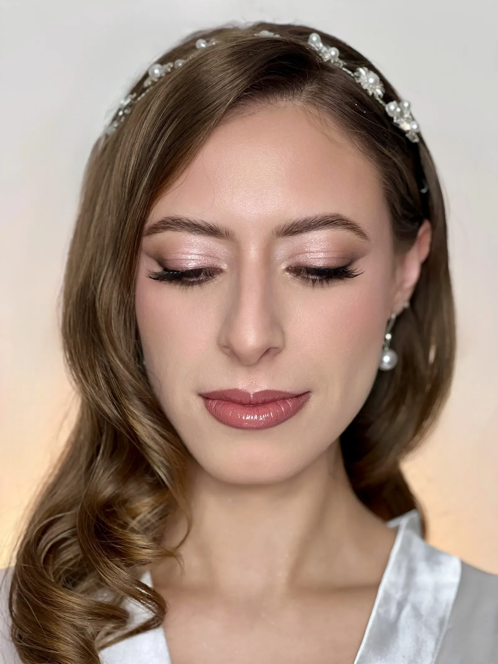 Primer plano de Lau con ojos cerrados: maquillaje de novia con sombra rosada, delineado y labios con brillo
