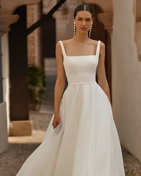 Bride in a minimalist white dress, with an updo and long pearl earrings.