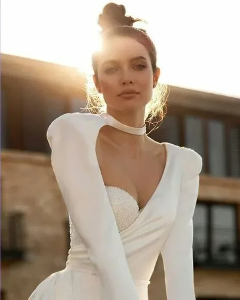Bride with natural makeup, an updo, and a white long-sleeved dress.