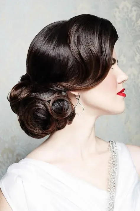 Perfil de una novia con recogido vintage de ondas, labios rojos y vestido blanco.