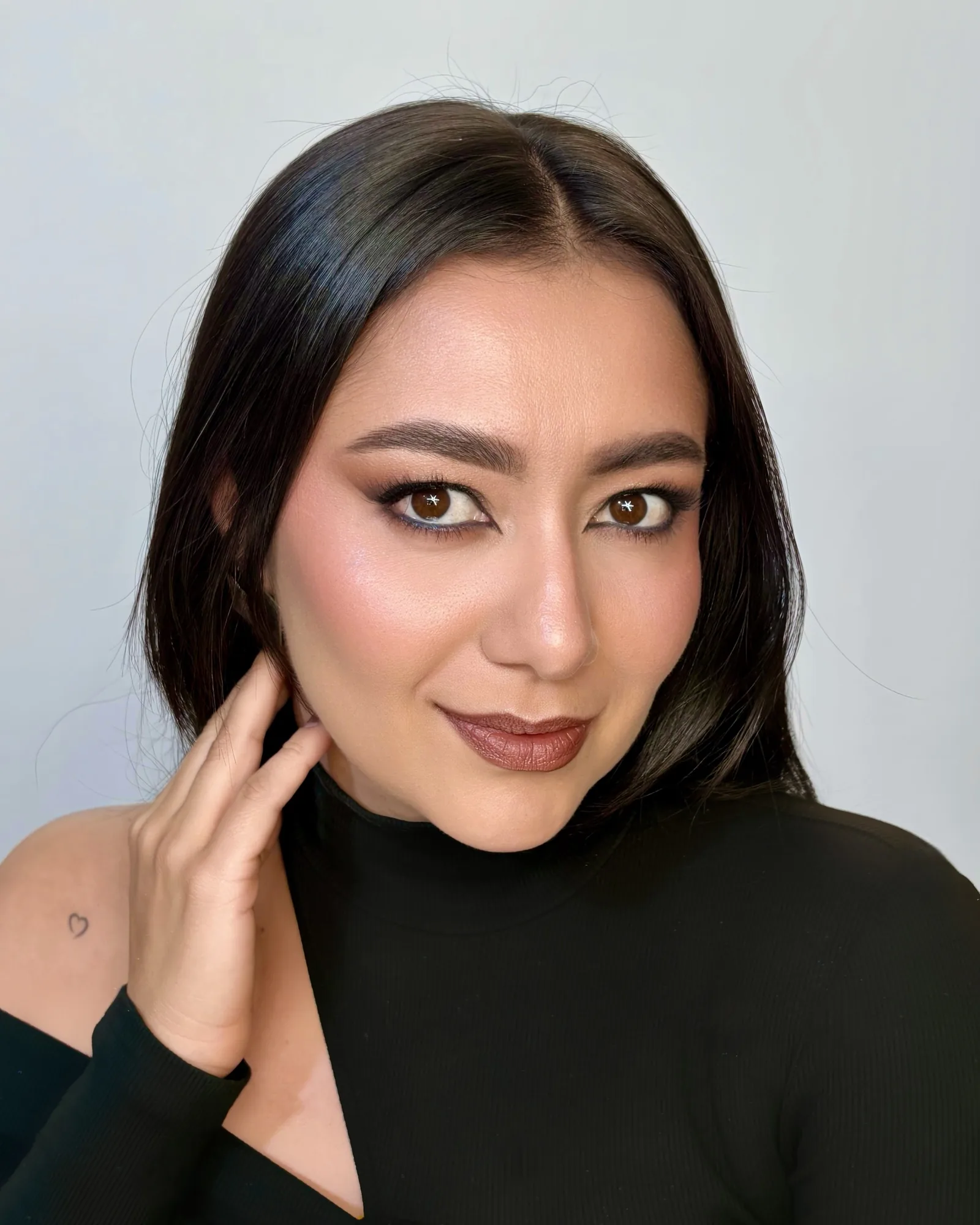 Retrato de una mujer con delineado negro, sombras cálidas y labios terracota.